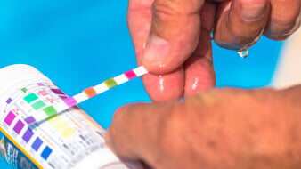 A test strip dipped into bright pool water